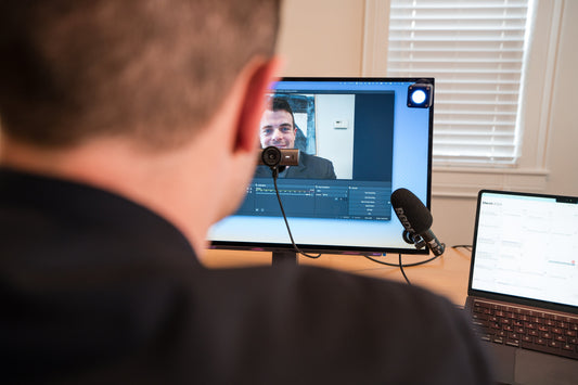 A professional desk setup with a webcam mounted at eye level on the monitor